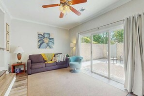 A spacious living room with a sofa, a chair, a ceiling fan, and a large sliding glass door leading to an outdoor area. - Beach Life Retreat Home (Myrtle Beach)