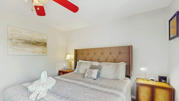 Een hotelkamer met een groot bed, een hoofdeinde, een nachtkastje met een lamp en een klein kastje.