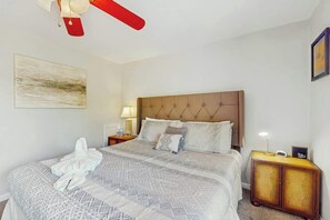 A hotel room with a large bed, a headboard, a bedside table with a lamp, and a small cabinet. - Beach Life Retreat Home (Myrtle Beach)