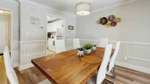 Een eetruimte met een houten tafel, witte stoelen en een hanglamp.
