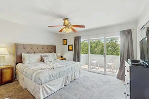 A bedroom with a bed, a ceiling fan, a TV, and a balcony with a chair. - Beach Life Retreat Home (Myrtle Beach)