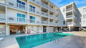 A multi-story hotel with a swimming pool, outdoor seating, and a lifeguard stand. - Ocean Pier IV Unit - 332 (North Myrtle Beach)