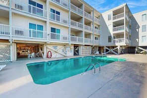 A multi-story hotel with a swimming pool, outdoor seating, and a lifeguard stand. - Ocean Pier IV Unit - 332 (North Myrtle Beach)