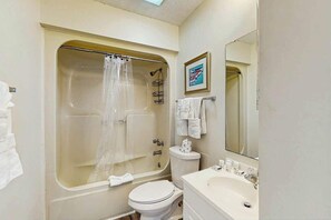 Ein Badezimmer mit Badewanne, Toilette, Waschbecken und einem gerahmten Bild an der Wand.