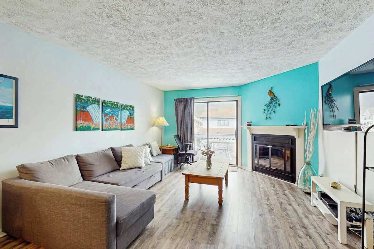 A living room with a sofa, a coffee table, a fireplace, and artwork on the walls.
