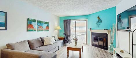 A living room with a sofa, a coffee table, a fireplace, and artwork on the walls.