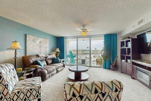 Una sala de estar con sofá, sillón y una mesita de centro. Hay un televisor y un mueble en la habitación.