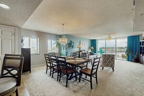A dining area with a table and chairs, a chandelier, and a view through a glass door to the outside. - Yacht Club Villas 1-501 (North Myrtle Beach)