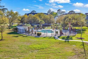 A fenced outdoor area with a pool, surrounded by trees and a pathway. - Coastal Retreat at Magnolia Place (Myrtle Beach)