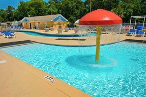 A swimming pool with a water fountain feature, lounge chairs, and a building in the background. - Renaissance Luxe | Two Sixteen C (Myrtle Beach)