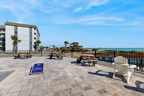 Eine Terrasse mit Picknicktischen und einem Fahrradweg mit Blick auf ein Gewässer.