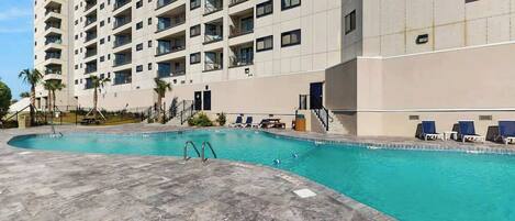 A swimming pool adjacent to a high-rise building with multiple balconies.