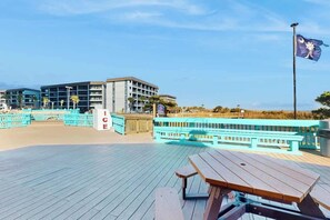 A beachside hotel with a wooden deck, picnic tables, and a flag. - Renaissance Luxe | Two Sixteen C (Myrtle Beach)