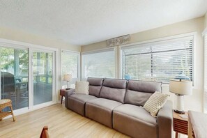Un salon avec un canapé beige, une lampe et un panneau indiquant « Maison de plage ».