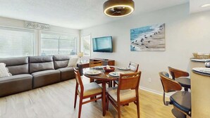 Een moderne woonkamer met een bank, eettafel, stoelen en een televisie.