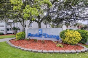 A sign for 'Arcadian Dunes' with a landscaped area featuring a hedge and mulch. - Arcadian Dunes 04-213 (Myrtle Beach)