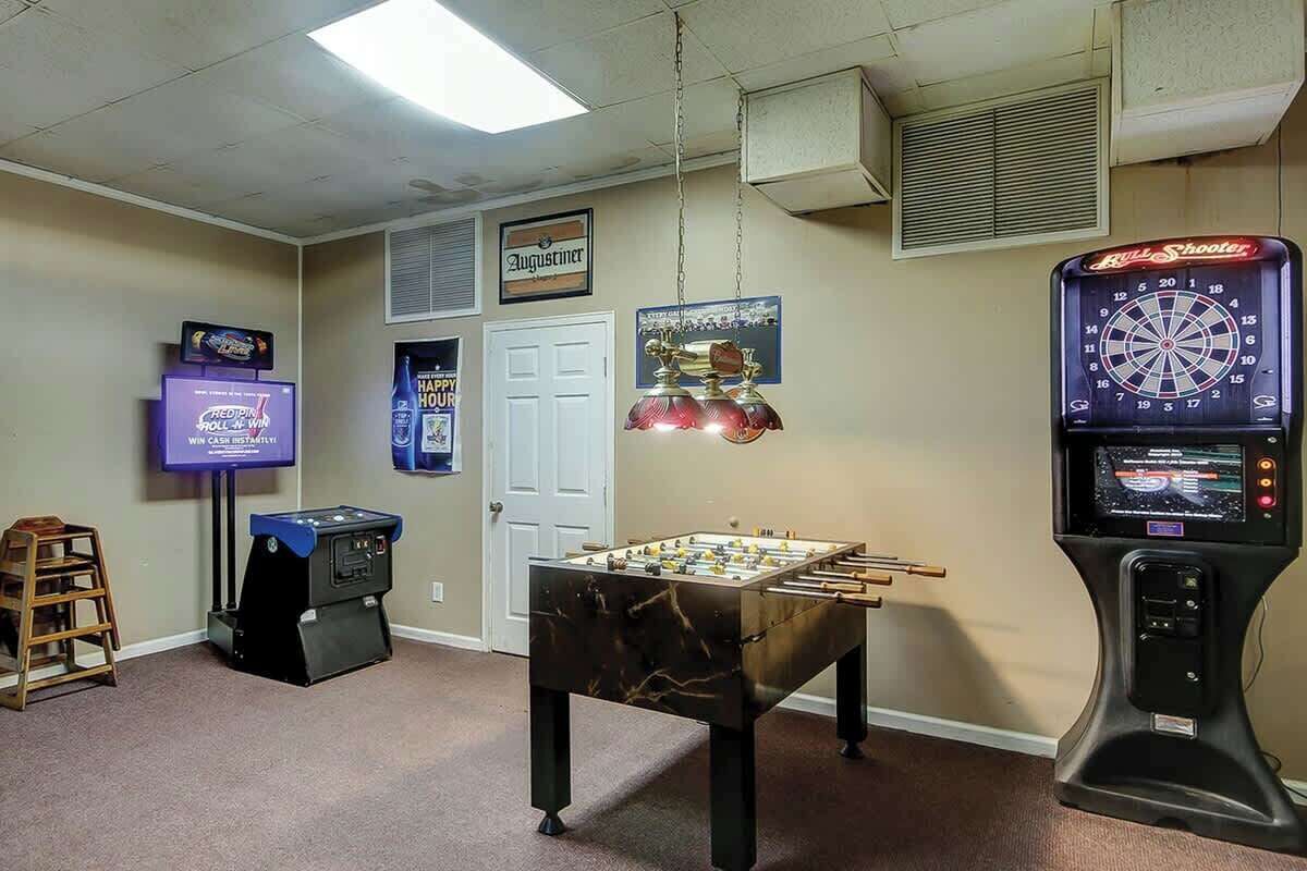 A room with a foosball table, a dartboard, and a television.