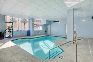 Ein Hallenbad mit freiem Blick nach draußen, einer Rettungswache und einem Schild, das das Tauchen untersagt.