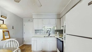 Eine Küche mit weißen Schränken, einer doppelten Spüle und einem Kühlschrank.