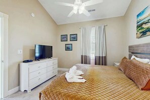 A bedroom with a bed, a television on a dresser, and a ceiling fan. - Magnolia Place at Myrtlewood (Myrtle Beach)