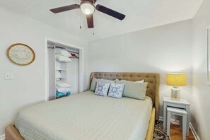 A bedroom with a bed, a ceiling fan, a bedside table with a lamp, and a wardrobe. - Ocean Pier 3 Unit - 322 (North Myrtle Beach)