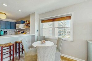 A modern kitchen with a dining area, a large window with a view, and a round table with chairs. - Ocean Pier 3 Unit - 322 (North Myrtle Beach)