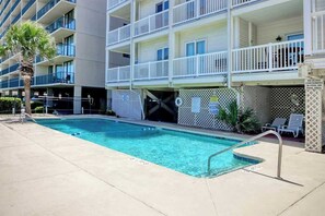 A swimming pool adjacent to a multi-story hotel with balconies. - Ocean Pier 3 Unit - 322 (North Myrtle Beach)
