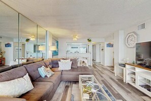 Ein Wohnzimmer mit einer Eckcouch, einem Couchtisch und einem Fernseher.