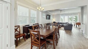 A spacious living room with a large dining table, comfortable seating, and a flat-screen TV mounted on the wall. - Cloisters on the Ocean 326 (Myrtle Beach)