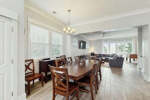 A spacious living room with a large dining table, comfortable seating, and a flat-screen TV mounted on the wall. - Cloisters on the Ocean 326 (Myrtle Beach)