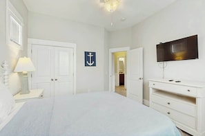 A bedroom with a bed, a TV, a dresser, a nightstand, a lamp, and a door. - Cloisters on the Ocean 326 (Myrtle Beach)