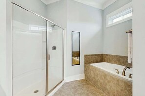 Ein modernes Badezimmer mit einer gläsernen Duschkabine, einer großzügigen Badewanne und einem Spiegel.
