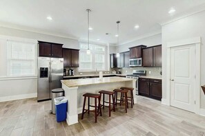 A modern kitchen with a central island, dark wood cabinets, stainless steel appliances, and pendant lighting. - Cloisters on the Ocean 326 (Myrtle Beach)