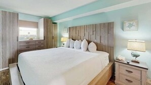 Ein Hotelzimmer mit einem großen Bett, Nachttischen, einem Kleiderschrank und einem Fenster mit Vorhängen.