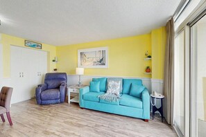 A room with a blue sofa, a purple armchair, and a white door. - Bay Watch Resort 0538 (North Myrtle Beach)
