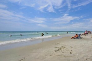 A beach with people swimming and sunbathing, and a clear sky. - Ashworth Unit 1305 Condo (North Myrtle Beach)