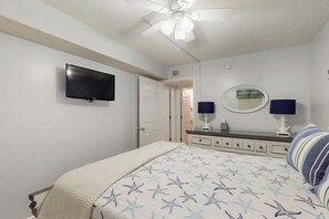 A bedroom with a bed, a ceiling fan, a television, a dresser, and a mirror. - Ashworth Unit 1305 Condo (North Myrtle Beach)