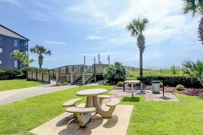A courtyard with a picnic table and benches, a staircase, and a building in the background. - Ashworth Unit 1305 Condo (North Myrtle Beach)