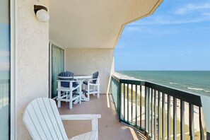 A balcony with a table and chairs, overlooking a beach. - Ashworth Unit 1305 Condo (North Myrtle Beach)