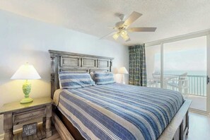 A bedroom with a large bed, a ceiling fan, and a view of the ocean through a sliding door. - Ashworth Unit 1305 Condo (North Myrtle Beach)