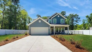 A two-story house with a garage, a covered porch, and a well-maintained lawn. - Pawleys Paradise Retreat (Pawleys Island)