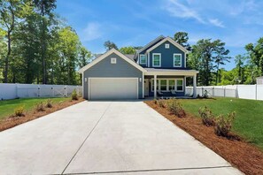 A two-story house with a garage, a covered porch, and a well-maintained lawn. - Pawleys Paradise Retreat (Pawleys Island)