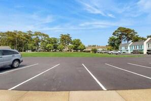 A parking lot with marked spaces, a parked car, and buildings in the background. - Robbers Roost Unit 831 (North Myrtle Beach)