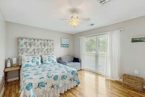 A bedroom with a bed, a ceiling fan, a window with blinds, and a bedside table. - Robbers Roost Unit 831 (North Myrtle Beach)
