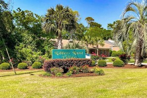A sign for 'Robbers Roost Villas' with a well-maintained garden and palm trees. - Robbers Roost Unit 831 (North Myrtle Beach)