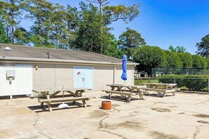 A building with picnic tables and a covered area, surrounded by trees. - Robbers Roost Unit 831 (North Myrtle Beach)