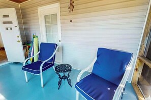 A room with two blue chairs, a small round table, and a white door. - Williams Beach Bunker A (North Myrtle Beach)