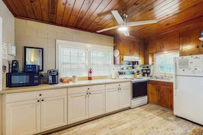 Eine Küche mit Holzausstattung, einer Mikrowelle, einer Kaffeemaschine, einem Herd und einem Kühlschrank.