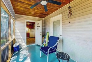 A covered porch with a ceiling fan, a blue chair, and a small table. - Williams Beach Bunker A (North Myrtle Beach)