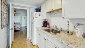 A kitchen with white cabinets, a granite countertop, a sink, and a coffee maker. - Palms Resort Unit 404 (Myrtle Beach)